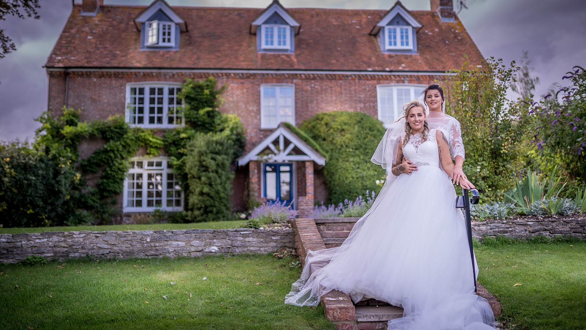 same sex wedding coulple in their wedding dresses in front of a house